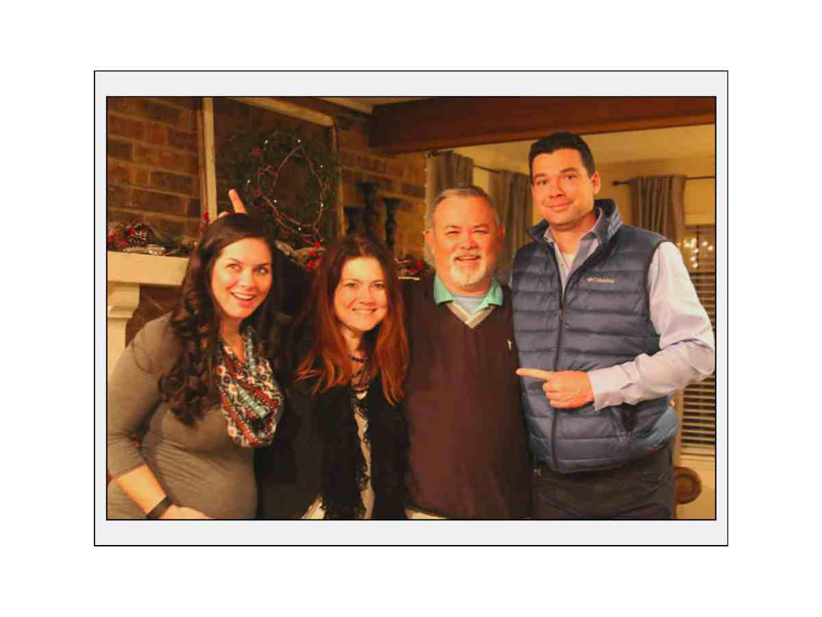 christmas photos with siblings Four people posing together indoors, three women and one man, all smiling.