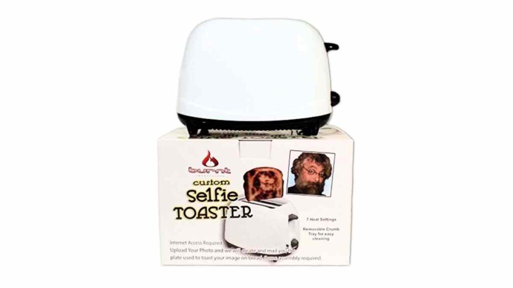 selfie toaster unique gift idea A custom selfie toaster box with an image of a white toaster on top and a photo of a man's face next to a slice of toast featuring a burned image of his face. The label mentions 7 heat settings and a removable crumb tray.