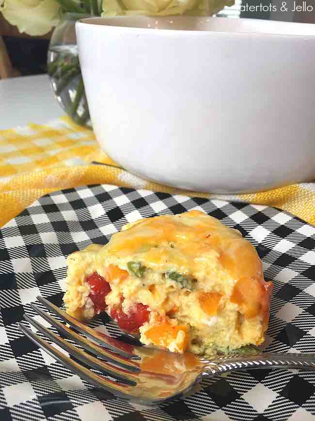 pressure cooker veggie crustless quiche A delightful slice of cheesy veggie casserole sitting on a stylish black and white plaid plate, teasingly close to a fork ready to dig in, with a mood-setting bouquet in the background.