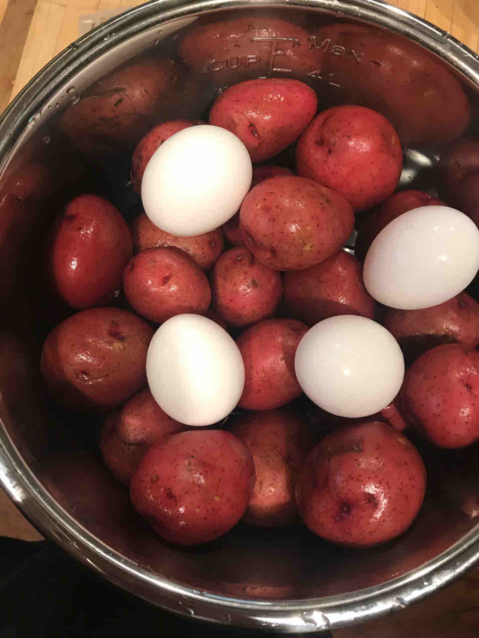 potato salad 2 A metal pot filled with round, blushing red potatoes and a few stark white eggs, looking like a culinary meeting of the spuds and the notsospuds, ready to hatch a delicious plan.