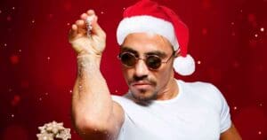 A Christmas meme featuring a man in sunglasses and a Santa hat doing a stylish sprinkle of holiday cheer, with gingerbread cookies in the corner.