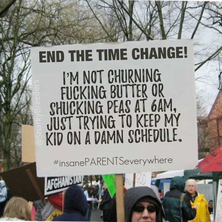time change A humorous protest sign at a rally reads, 'End the Time Change! I’m not churning butter or shucking peas at 6am, just trying to keep my kid on a damn schedule. #insanePARENTSseverywhere' amid a crowd of bundledup people.