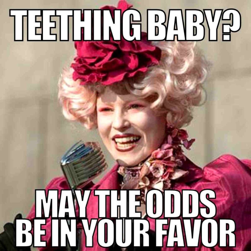 baby teething meme A woman in flamboyant attire reminiscent of 'The Hunger Games' is smiling, holding a microphone, with text saying 'Teething Baby? May the odds be in your favor,' humorously suggesting parental challenges, perfect for Thursday's endless memes.