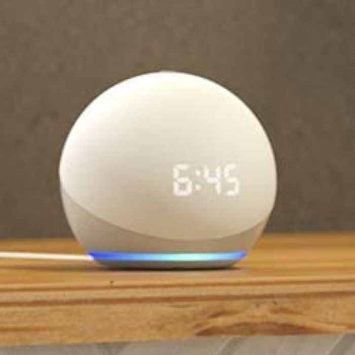 amazon echo dot kid smart alarm clock A smart speaker (amazon echo dot kid smart alarm clock) with a digital clock displaying 6:45, placed on a wooden surface.