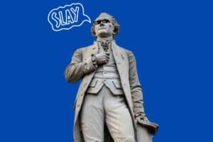 Statue of Alexander Hamilton wearing meme sunglasses with a speech bubble saying "Slay," set on a blue background for humor effect.
