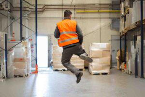 Meme of a worker in an orange safety vest doing a happy leap in a warehouse, embodying everyone's Friday afternoon mood as the weekend approaches.