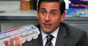 A humorous egg meme showing a man in an office holding a carton of large eggs, as if it's his most eggcellent idea yet.