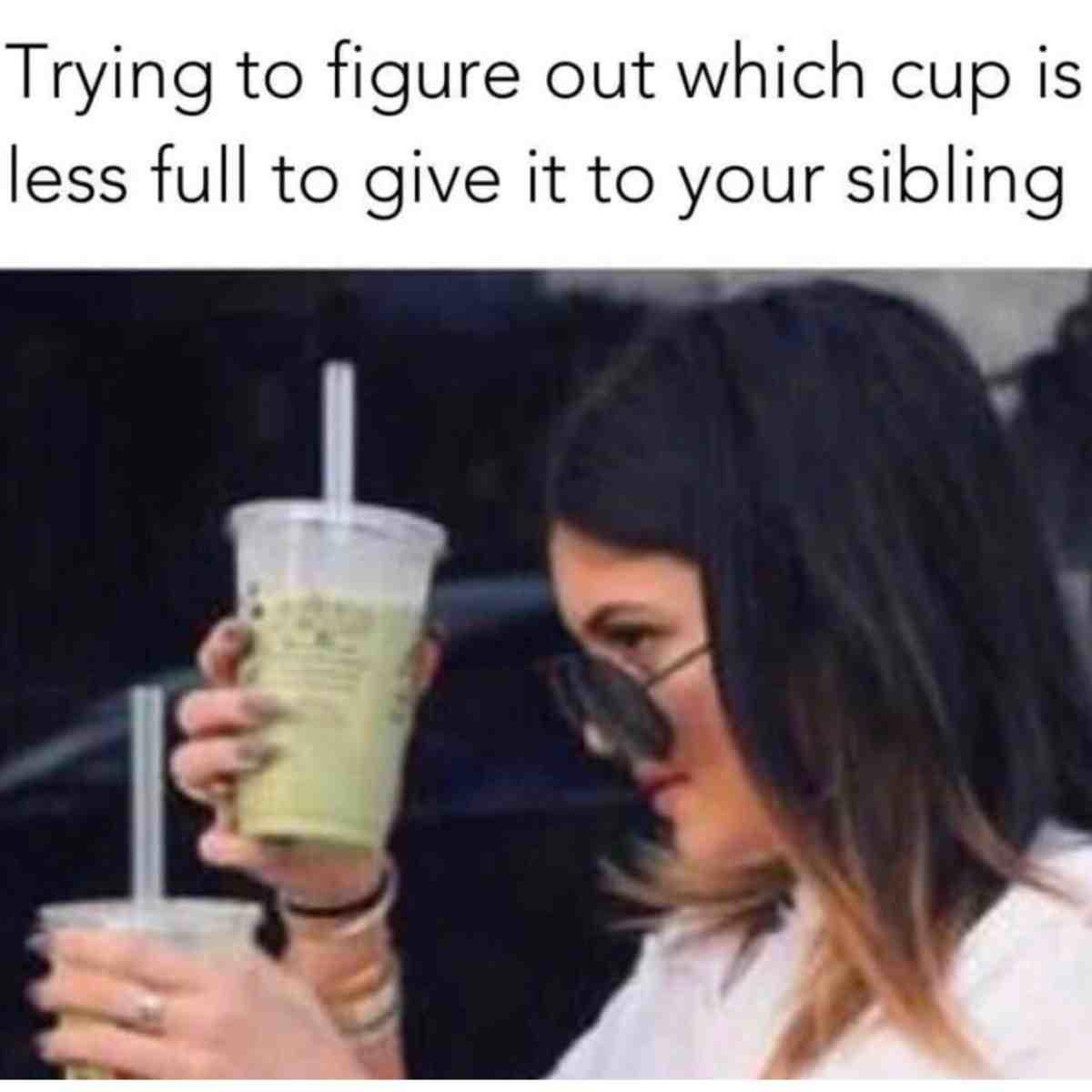 siblings meme petty Woman scrutinizing two cups of green juice, looking for the less full one to give to her sibling with a hilariously intense expression; the caption humorously reads, 'Trying to figure out which cup is less full to give it to your sibling,' capturing that classic sibling rivalry moment.