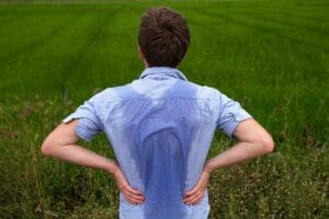 Meme of a man in a light blue shirt with a giant sweat stain on his back, looking ready to blame it on global warming or an epic hike, standing in a lush green field.