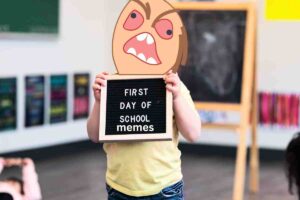 Kid with a cartoonishly angry face holding a sign that says 'First Day of School Memes,' perfectly capturing those Monday morning vibes.