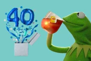 Kermit the Frog sipping tea with a smirk while blue '40' balloons pop out of a box, poking fun at turning the big 40.