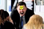 Grinning man in a suit with a 'Tuesday Work Memes' sticky note on his forehead, humorously expressing that Tuesday is as thrilling as a surprise meeting.
