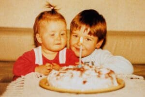 Classic sibling moment alert! A cheeky big brother and his skeptical little sister stare at a cake, watching the lone candle with the seriousness reserved only for birthday cakes and legendary brother memes.