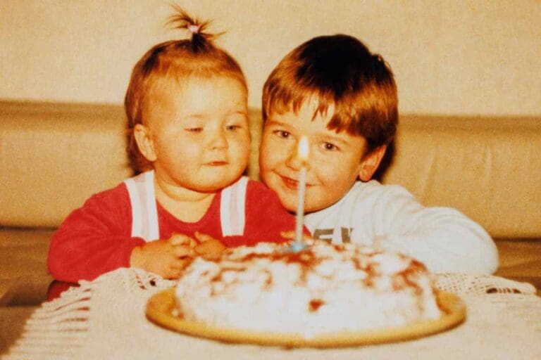 Classic sibling moment alert! A cheeky big brother and his skeptical little sister stare at a cake, watching the lone candle with the seriousness reserved only for birthday cakes and legendary brother memes.