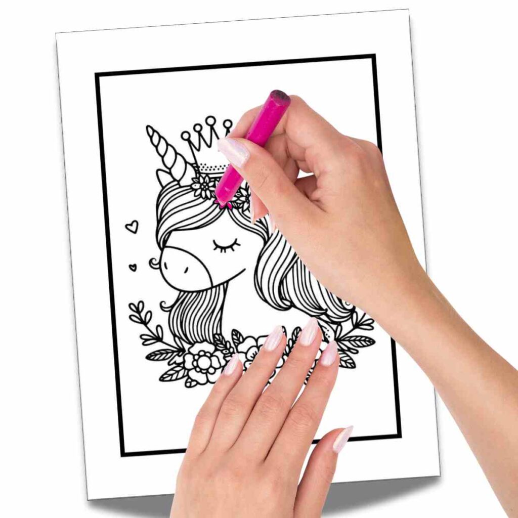 coloring a unicorn coloring sheet A person coloring a black and white drawing of a unicorn with a pink crayon. The unicorn features a crown and floral decorations, surrounded by leaves and hearts.