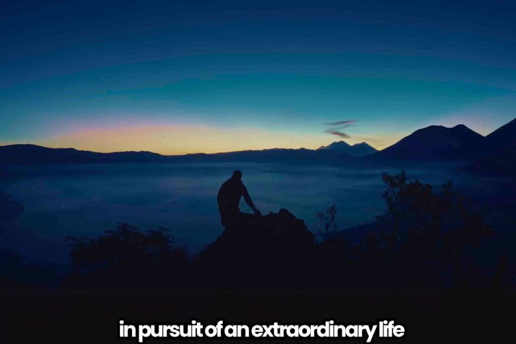 in pursuit of an extraordinary life Silhouette of a person sitting on a hilltop at dawn, overlooking a misty landscape with mountains in the distance, accompanied by the text 'in pursuit of an extraordinary life.'