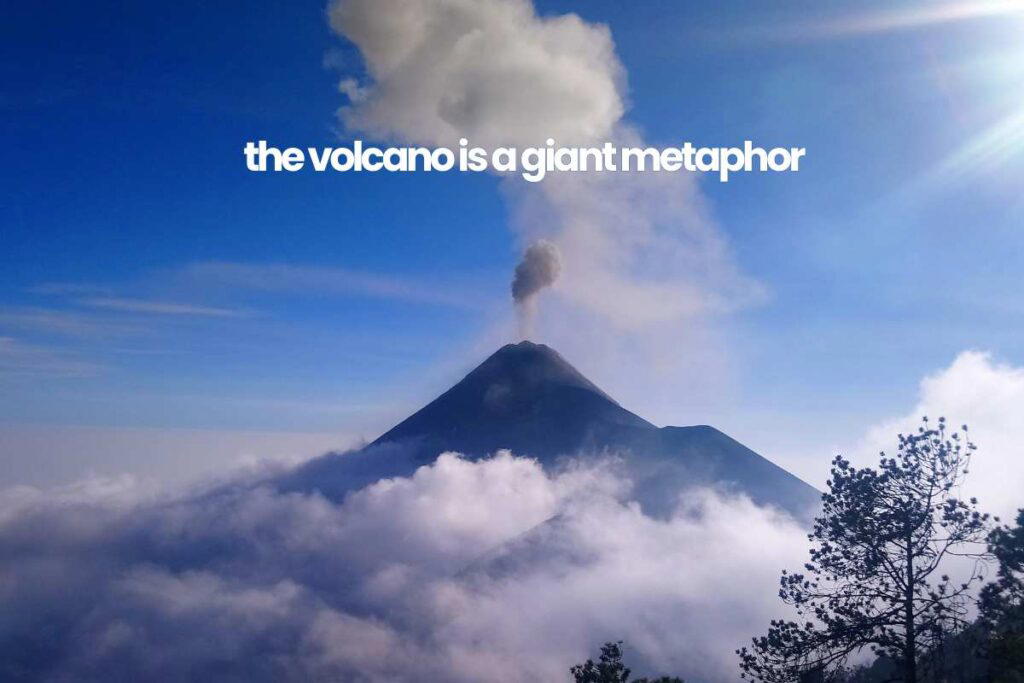 volcano in pursuit of an extraordinary life A volcano emits smoke against a blue sky with the words "the volcano is a giant metaphor" superimposed on the image.
